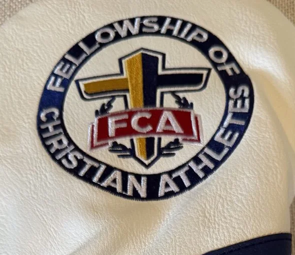 A close-up of the Fellowship of Christian Athletes crest embroidered on a white cover