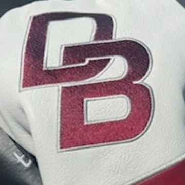 A close-up of a maroon DB monogram embroidered on a white cover
