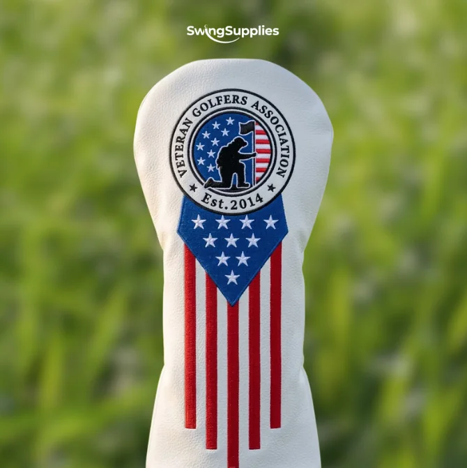 A white driver headcover with the Veteran Golfers Association crest above red and white stripes and a field of stars